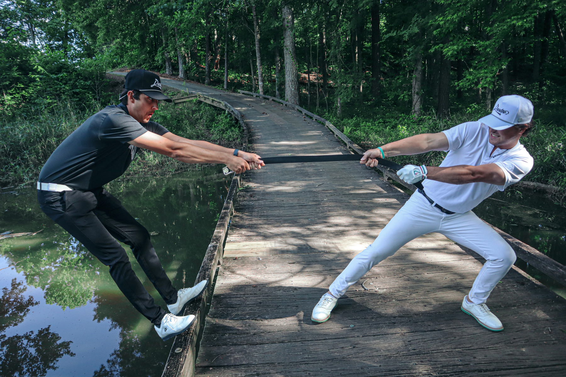 Two golfers on a Lowcountry bridge putting a Dartee ratchet belt to the test
